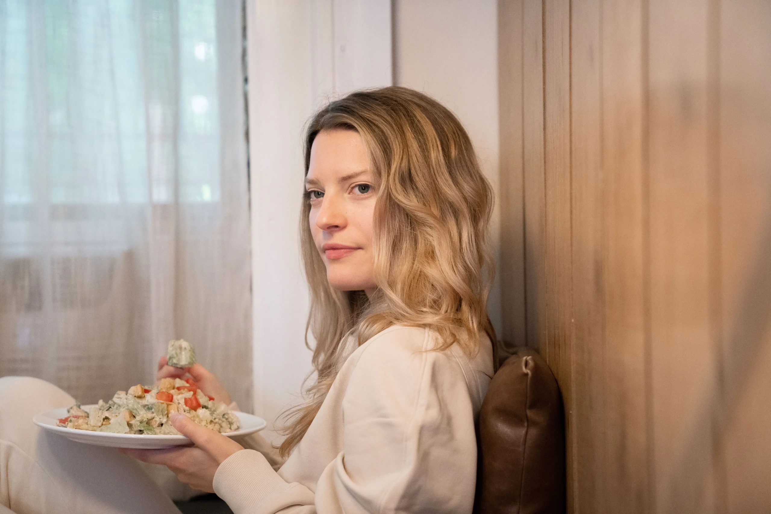 A blonde woman holding a plate of pasta salad